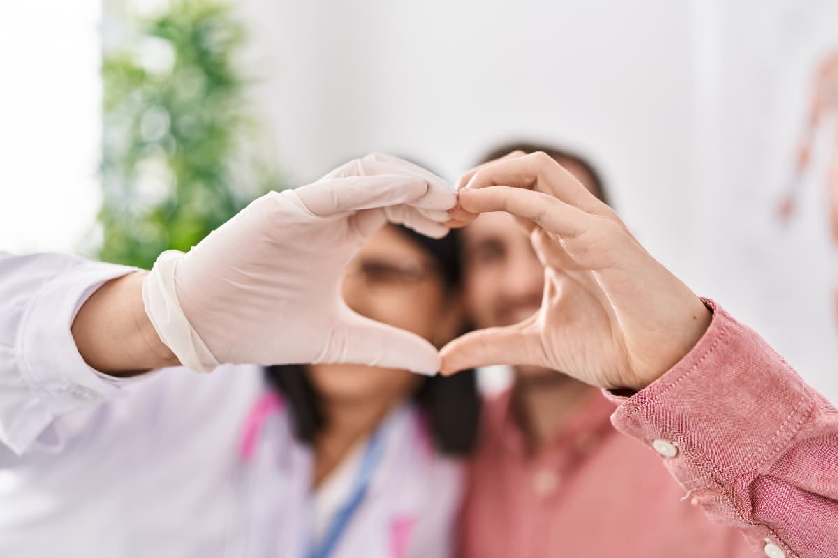 Medical professional and patient making heart with their hands